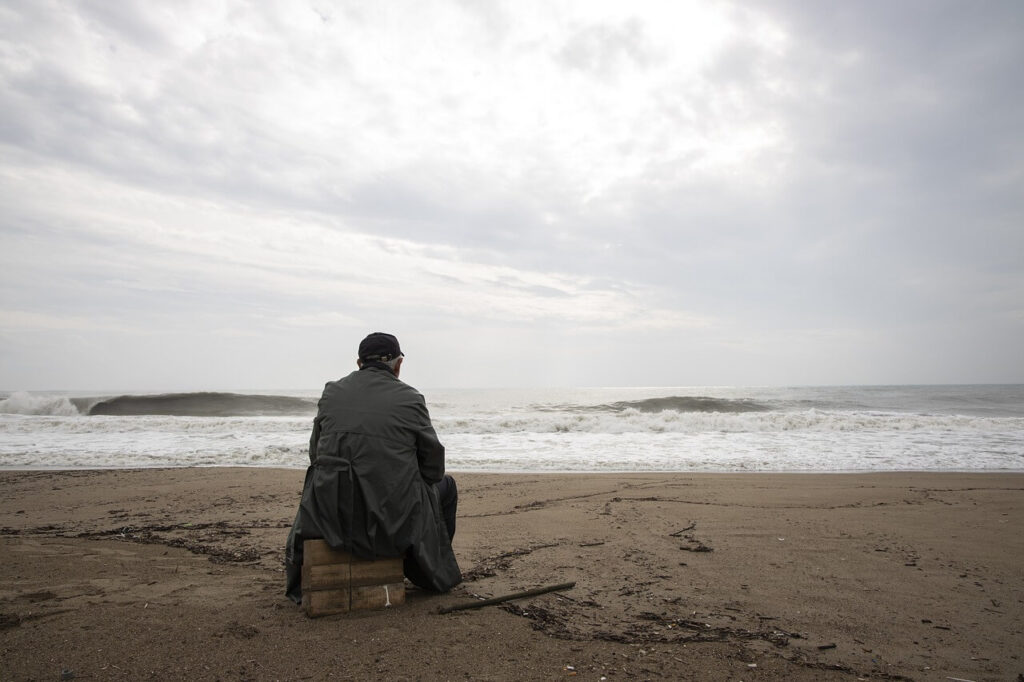 浜辺に座って海を眺めている男性