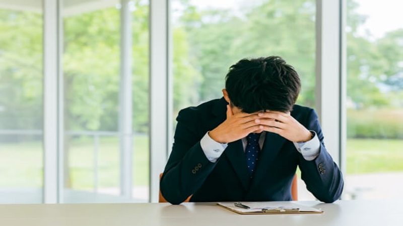 上司と合わないストレスに悩みうつむく男性ビジネスパーソン
