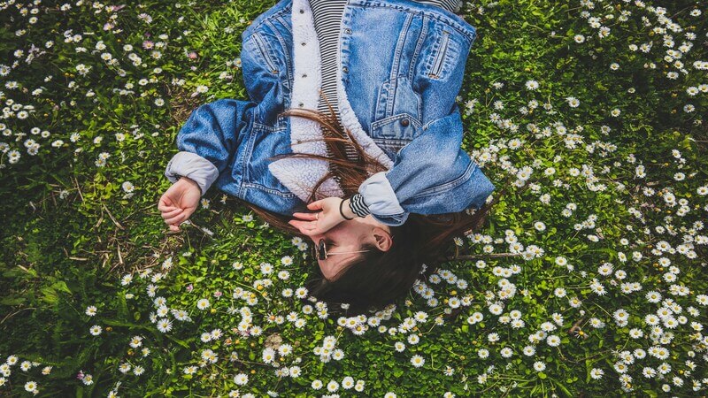 女性が花畑の上で寝転ぶ様子