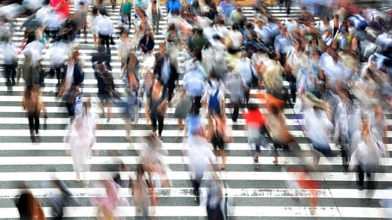 仕事の忙しさに追われる現代人が交差点を行き来する様子
