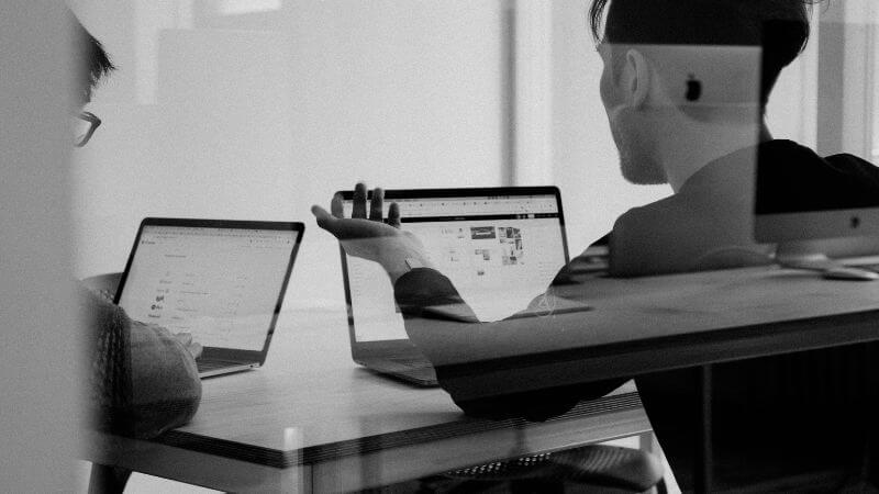 パソコンの前で会話する男性2人